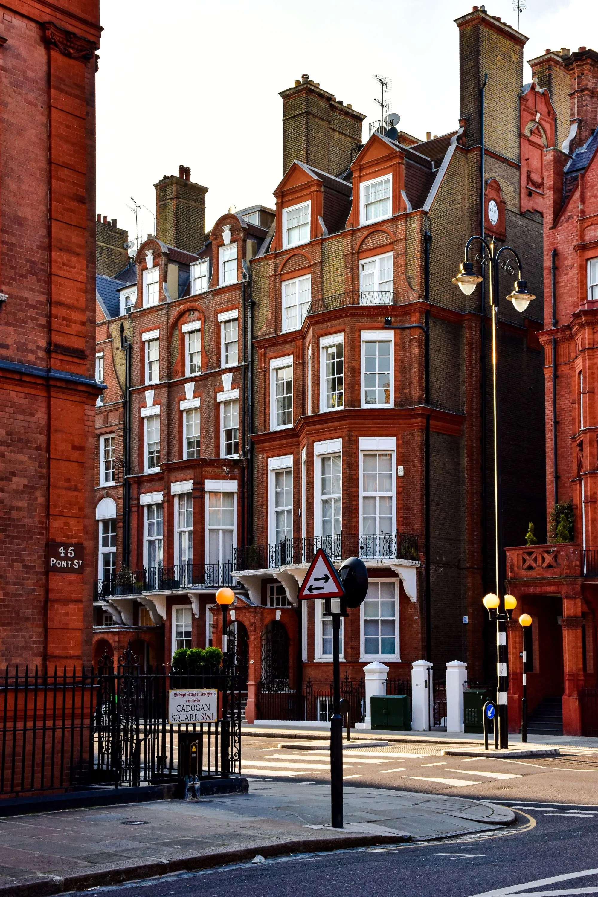 A row of red-brick Victorian townhouses on a London street at golden hour